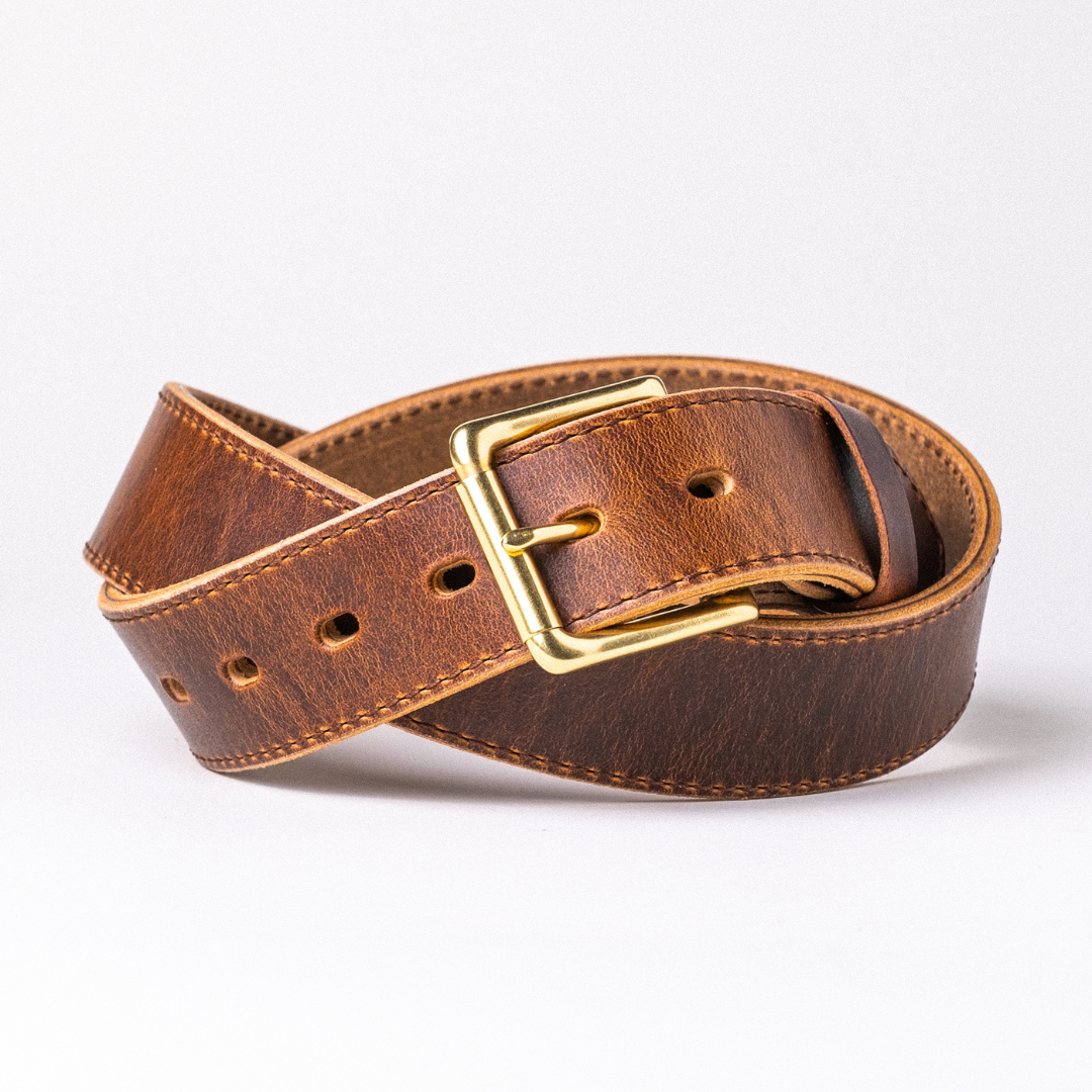 A coiled brown leather belt with a gold-tone metal buckle, displayed on a clean white background.