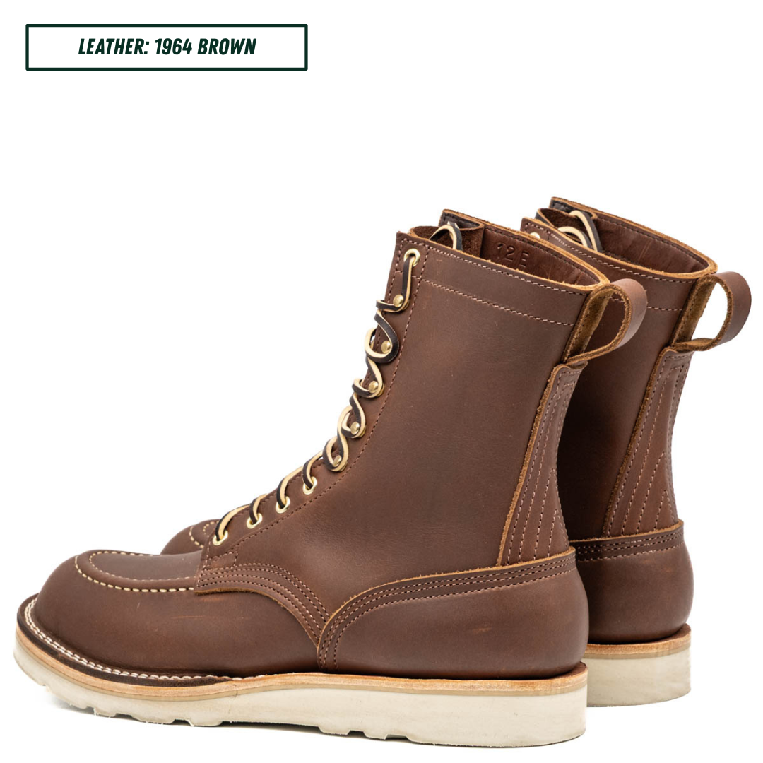 A pair of brown leather lace-up work boots with light tan stitching and off-white soles, shown on a white background with a text label in the top-left corner that reads 'LEATHER: 1964 BROWN'.
