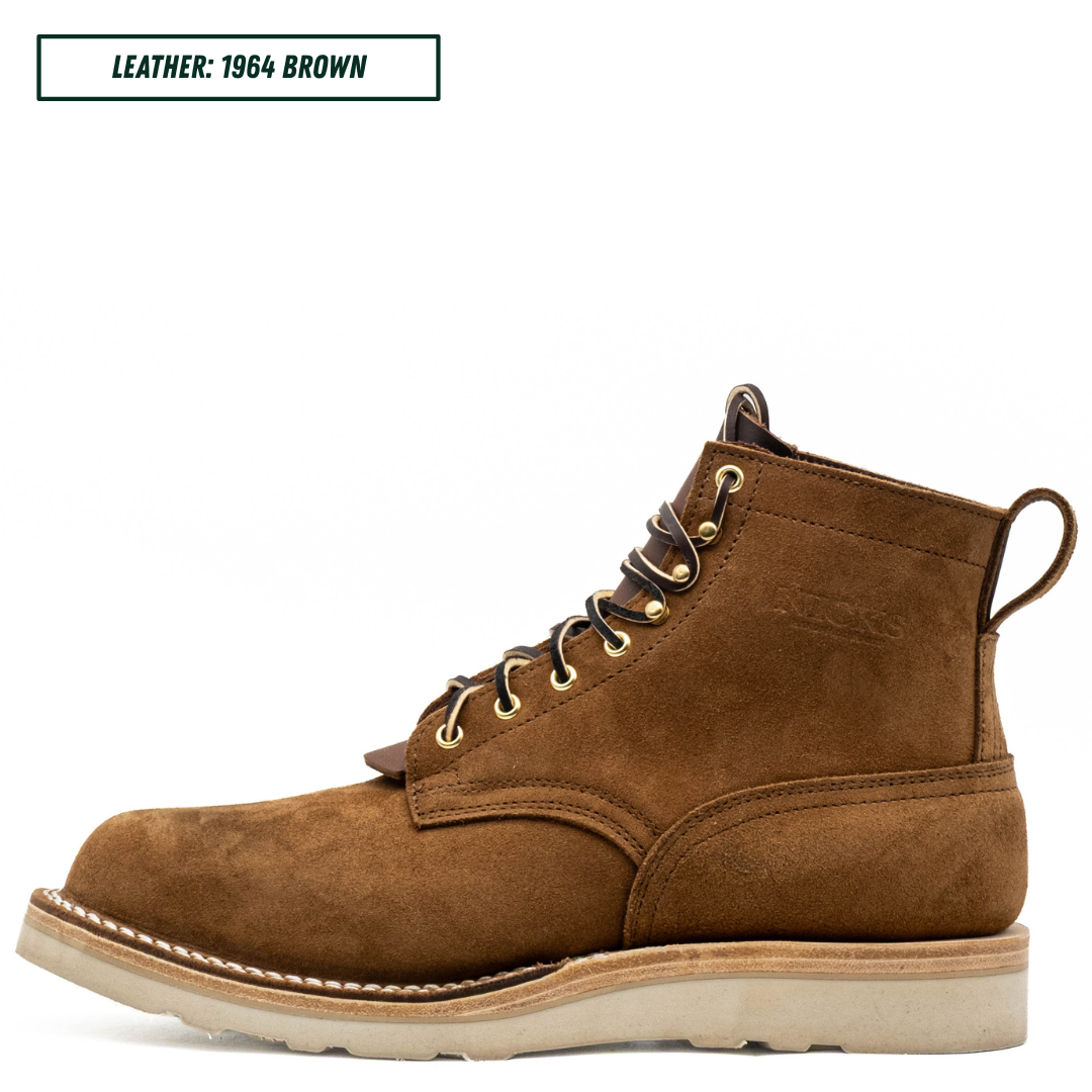 A single brown suede lace-up work boot shown in profile on a white background, with a small text label in the top-left corner reading 'LEATHER: 1964 BROWN'. The boot has tan stitching, a light beige sole, and gold-toned eyelets.