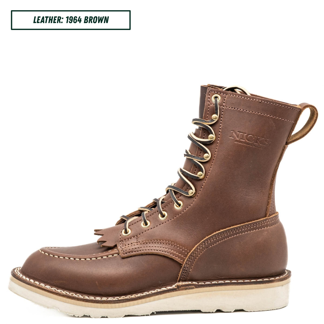 A single brown leather lace-up work boot shown in profile on a white background, with a small text label in the top-left corner reading 'LEATHER: 1964 BROWN'. The boot has brass eyelets, a pull tab, visible stitching, and a thick off-white sole.