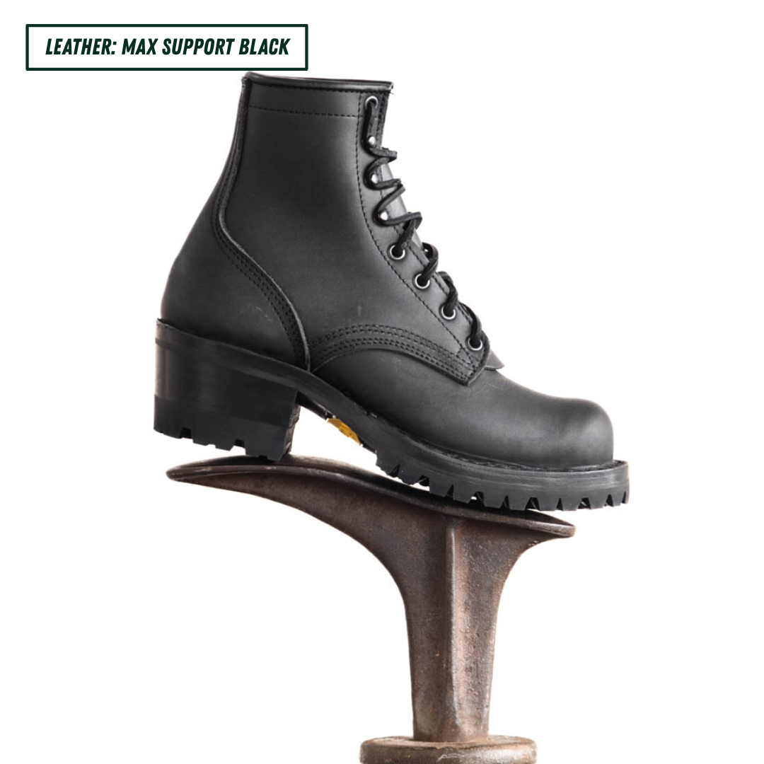 A black leather lace-up boot with a chunky lug sole and block heel, displayed on a metal shoe stand against a white background. A text label in the top-left corner reads 'LEATHER: MAX SUPPORT BLACK'.