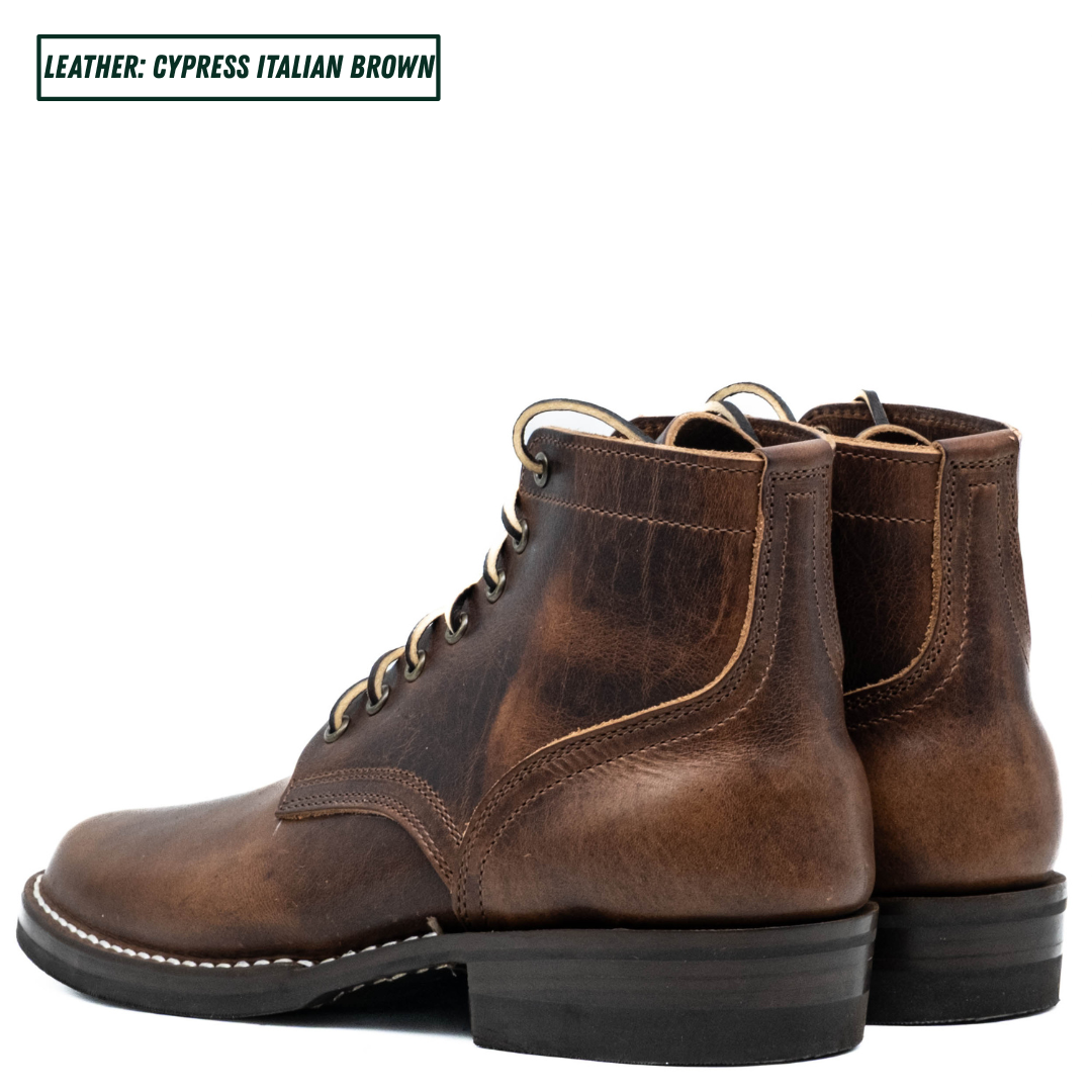 A pair of distressed brown leather lace-up ankle boots shown from a three-quarter angle on a white background, with a text label in the top-left corner reading 'LEATHER: CYPRESS ITALIAN BROWN'.