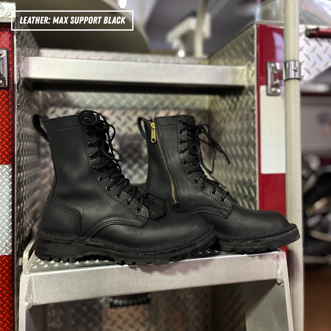 A pair of black leather lace-up combat boots with side zippers, displayed on a metal step inside a red and silver utility vehicle or storage rack.