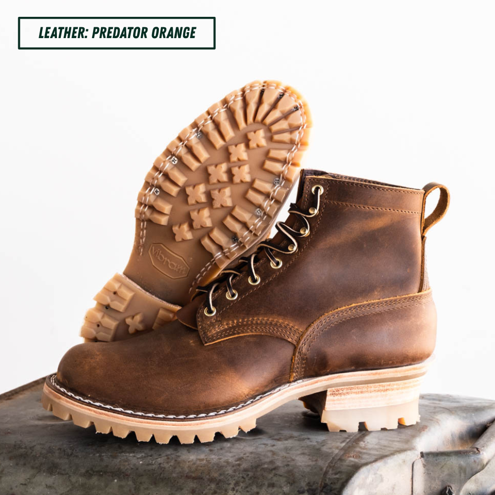 A pair of rugged lace-up ankle boots in distressed brown leather, with one boot standing upright and the other tilted to show the sole. The text 'LEATHER: PREDATOR ORANGE' appears in the top-left corner.