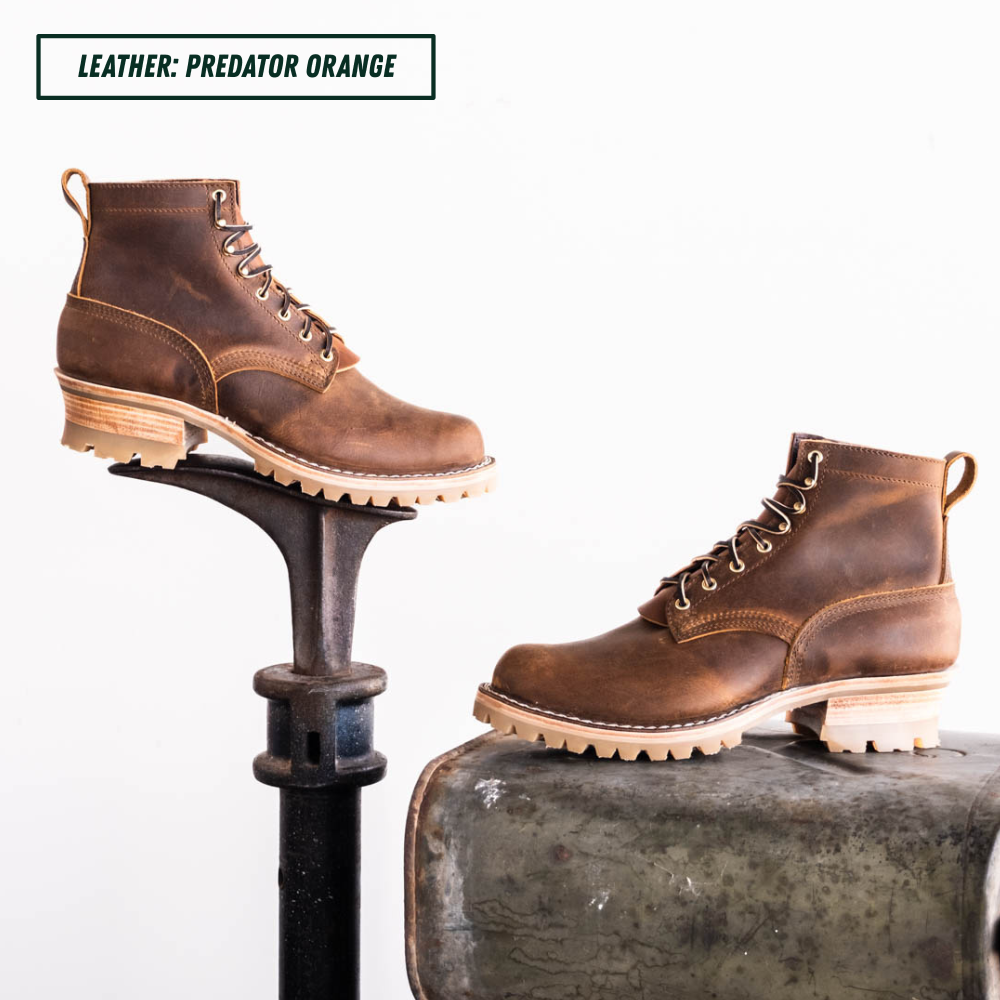 Two brown leather lace-up boots displayed on industrial metal stands against a white background, with a text label in the top left reading 'LEATHER: PREDATOR ORANGE'.