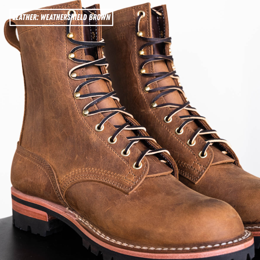 A pair of rugged lace-up work boots in weathered brown leather, shown on a clean white background with a black surface at the bottom. A text overlay in the top left reads 'LEATHER: WEATHERED BROWN'.