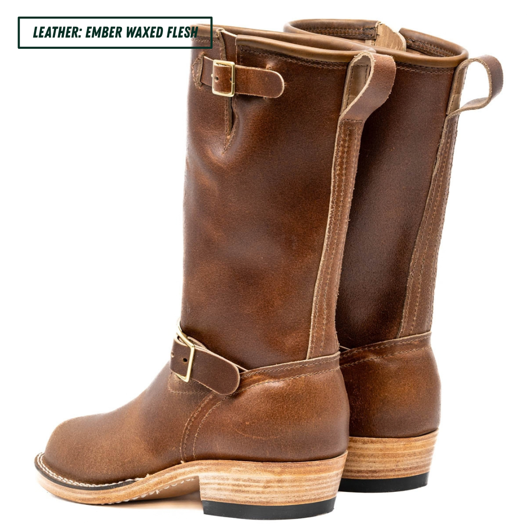A pair of mid-calf leather boots in a warm brown shade, featuring a stacked wood-look heel and brass buckle details, shown against a plain white background with a text label in the top left corner.
