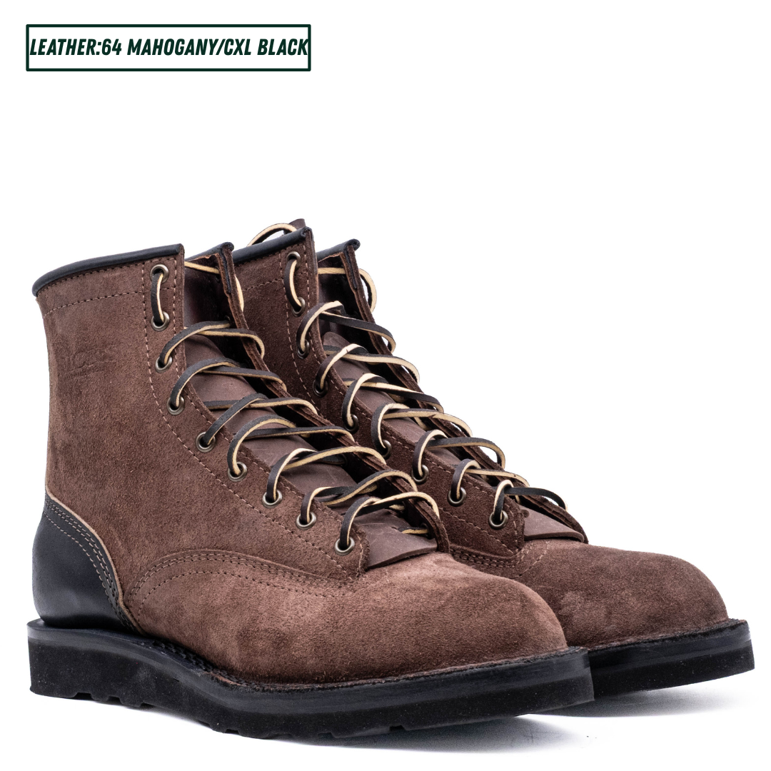 A pair of brown suede lace-up work boots with black leather single piece backstay. A text label in the top left reads 'LEATHER:64 MAHOGANY/CXL BLACK'.