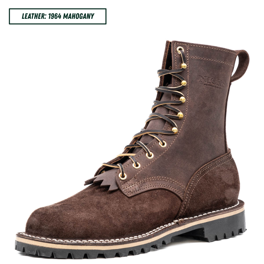 A dark brown suede lace-up boot shown in profile on a white background, with a text label in the top-left corner reading 'LEATHER: 1964 MAHOGANY'. The boot has brass eyelets and laces, a pull tab at the heel, and a thick black lug sole with a beige midsole.