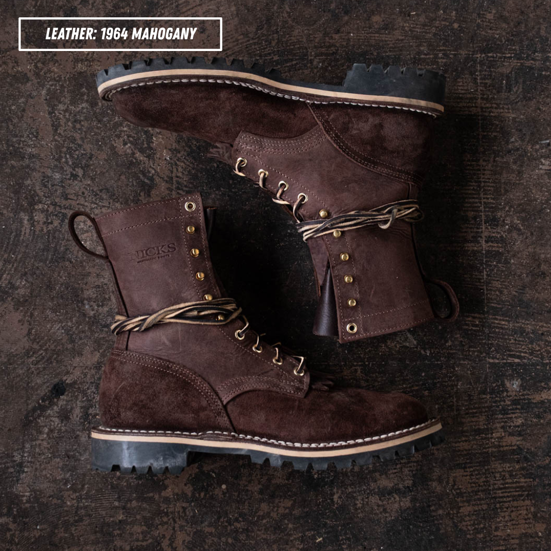 A pair of dark brown suede and leather lace-up boots arranged on a dark rustic wooden surface. The top-left corner includes a text label reading 'LEATHER: 1964 MAGOHAGNY'.