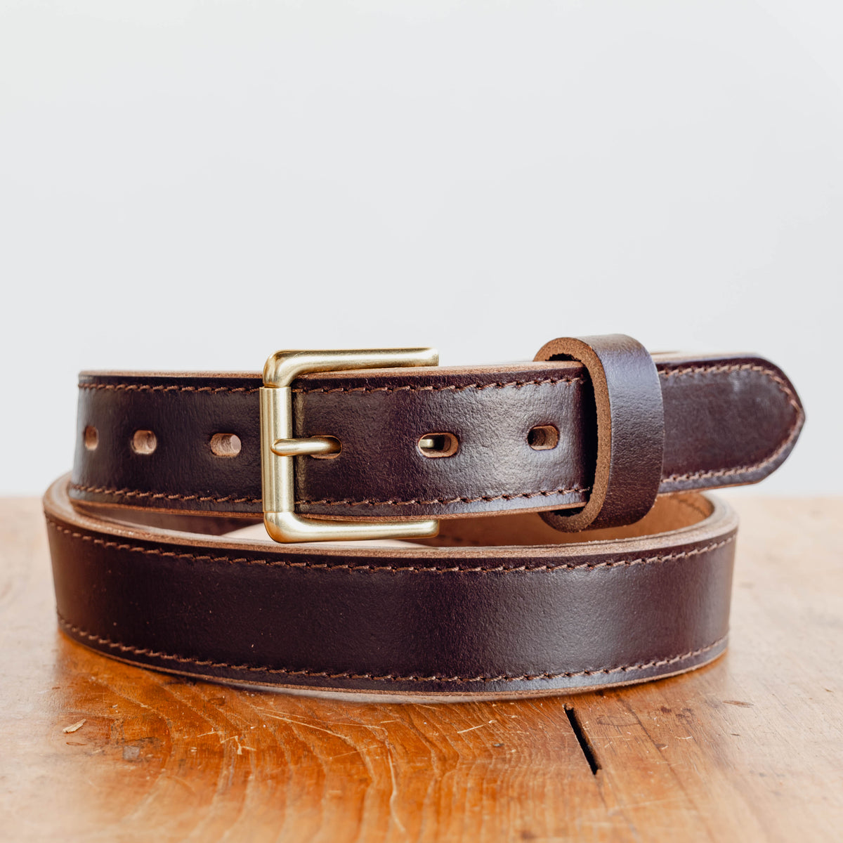 Java Waxed Flesh belt sitting on wooden table in front of white background