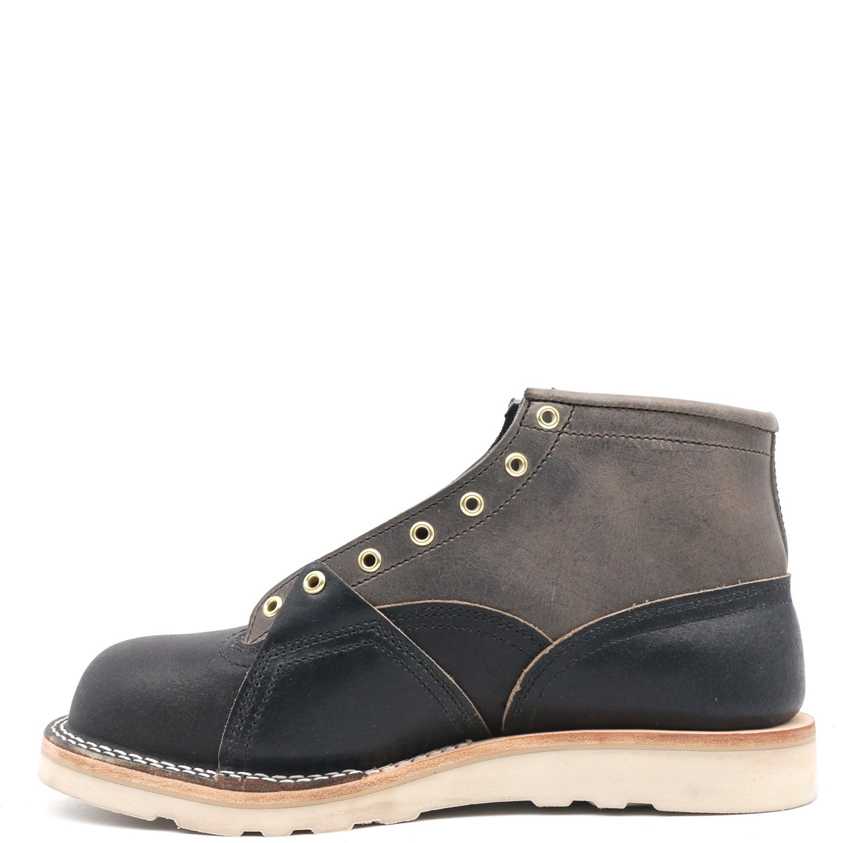 Photograph of the right inside of a gray and dark navy blue boot with leather details and an inside lineman patch on a white background
