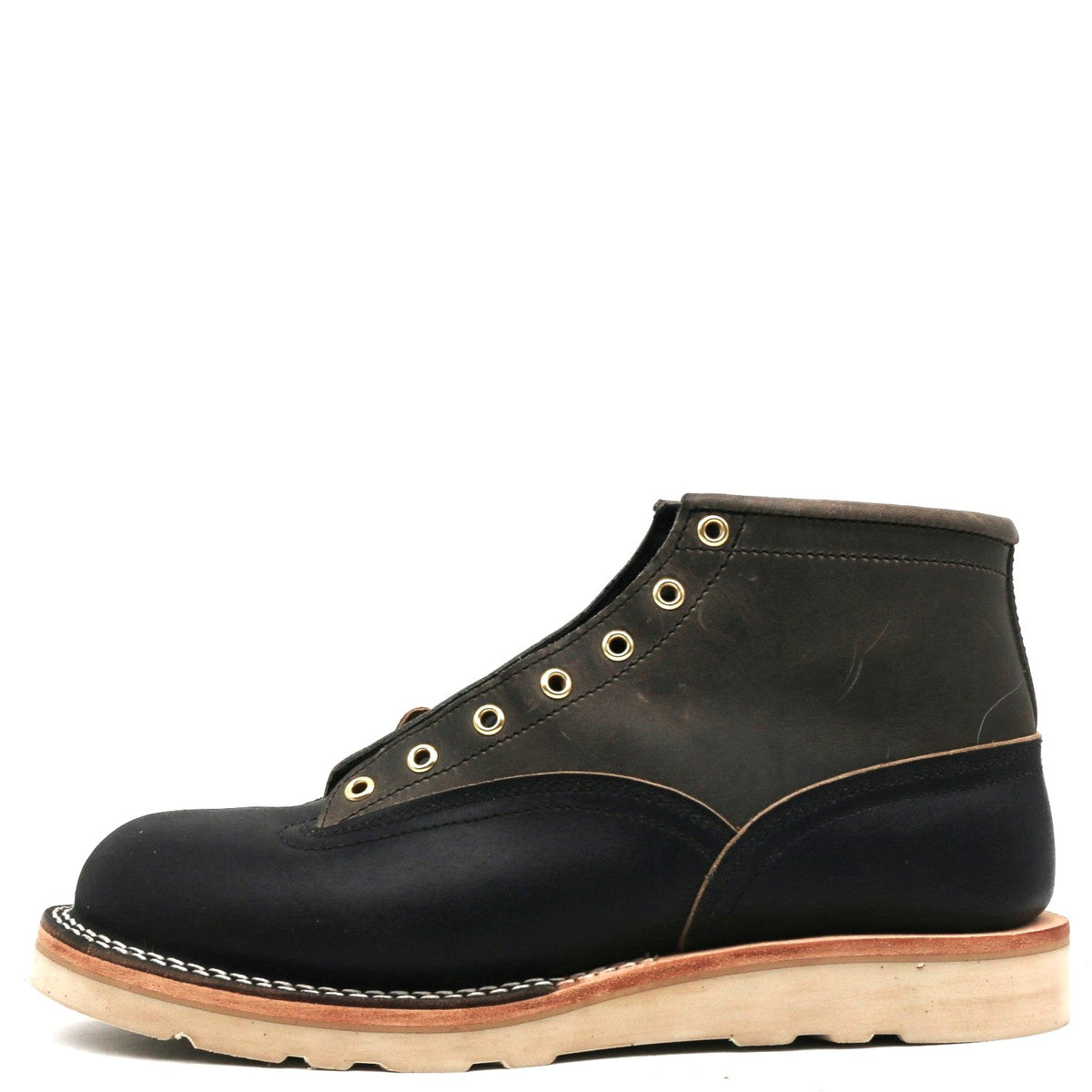 Grey and dark navy blue leather boot with brass hardware and a white wedge outsole in front of a white background.