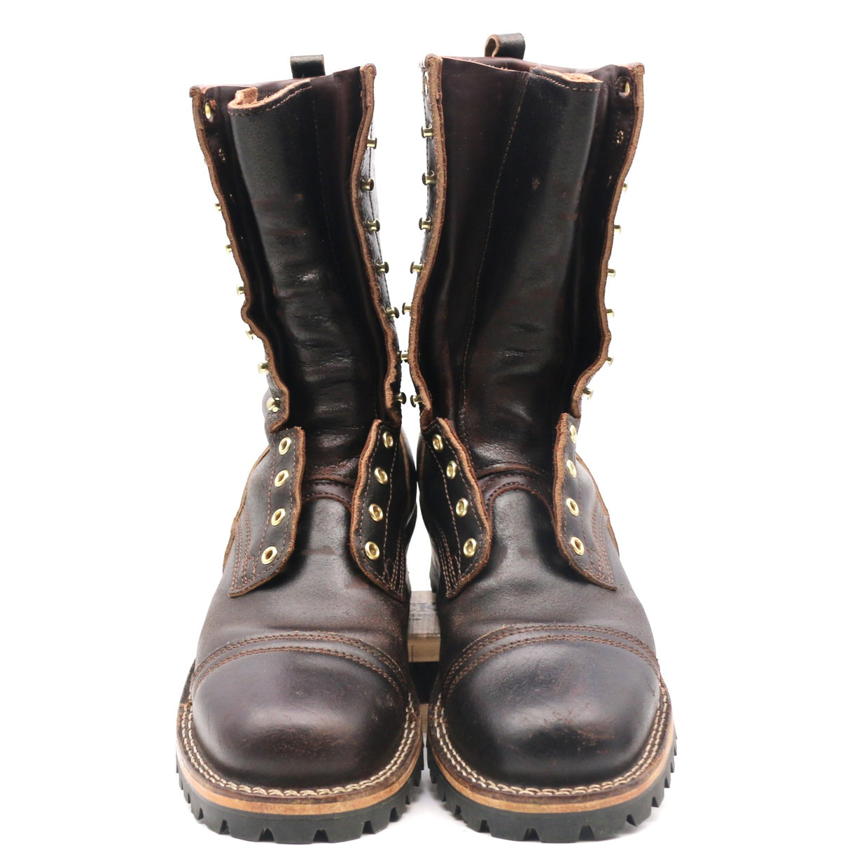 A pair of dark brown leather lace-up boots with metal studs and eyelets, shown from the front against a plain white background.