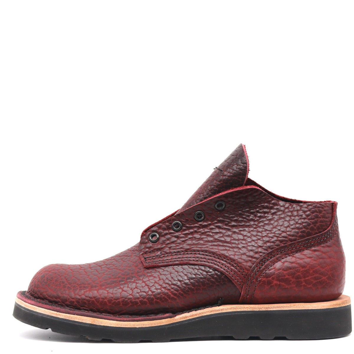 A single men's ankle boot in textured burgundy leather with a pebbled grain, featuring a black sole and a thin tan midsole layer, shown from a side profile on a white background.