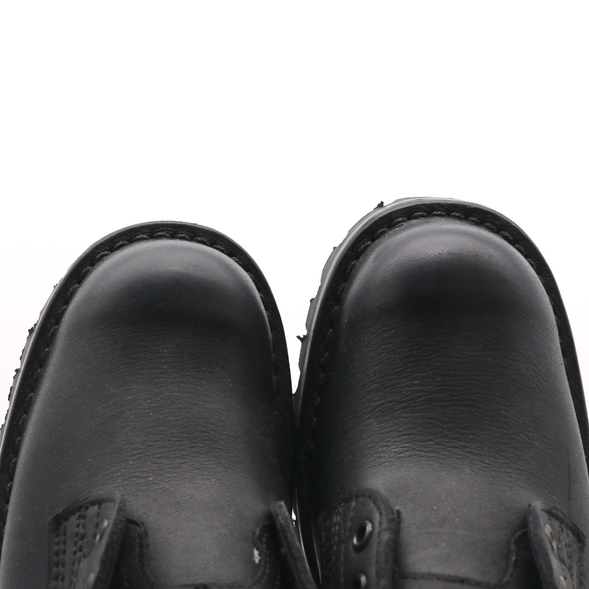 Close-up of a pair of black leather boots viewed from above against a white background. The right boot is clearly longer than the left.