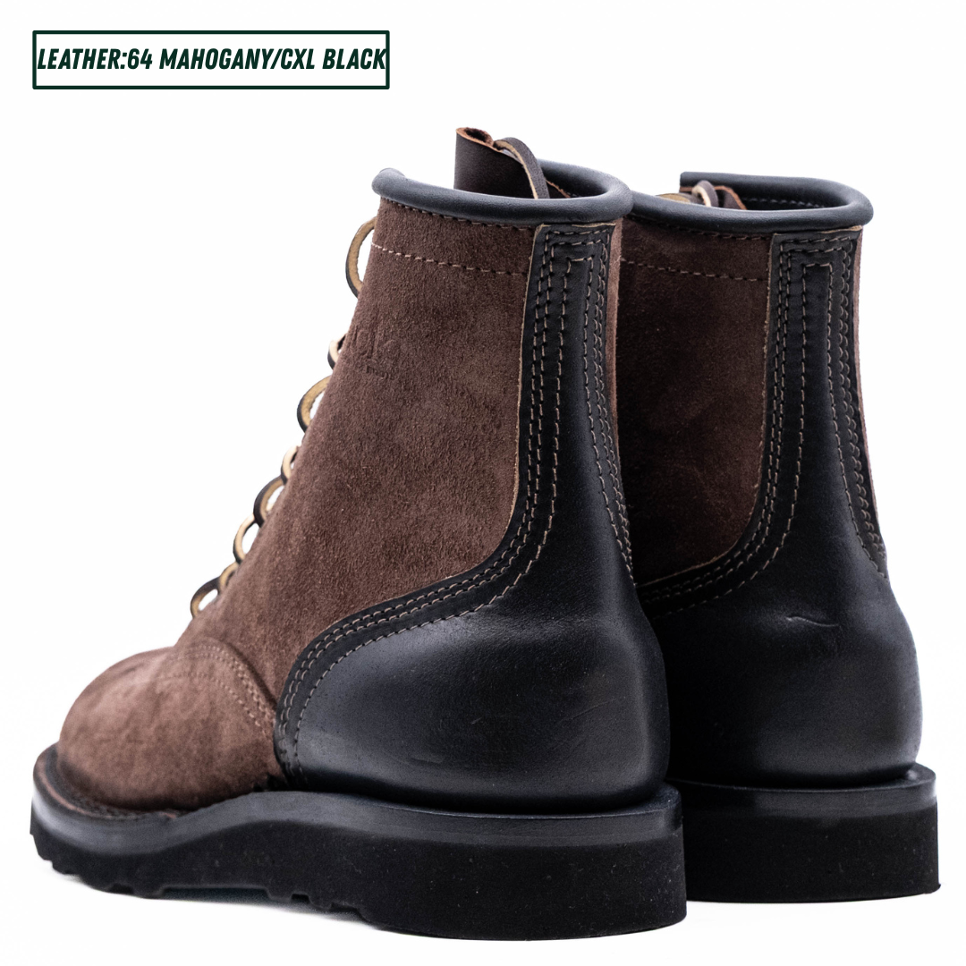 A pair of brown suede lace-up work boots with black leather single piece backstay. A text label in the top left reads 'LEATHER:64 MAHOGANY/CXL BLACK'.