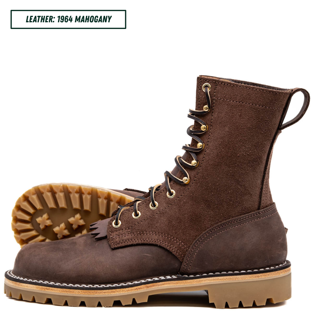 A dark brown suede lace-up boot shown from the side with the sole and outsole visible behind it, on a white background. A text label in the top left reads 'LEATHER: 1964 MAHOGANY'.