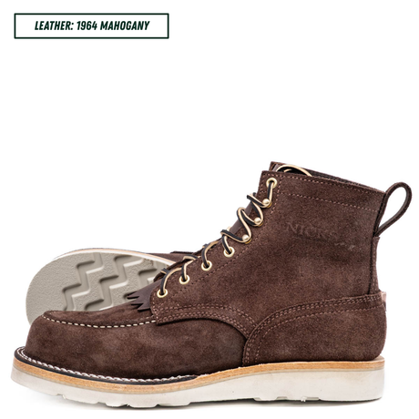 A single dark brown suede lace-up boot shown in side profile on a white background, with a second boot placed behind it to show the outsole. A small label at the top left reads 'LEATHER: 1964 MAHOGANY'.