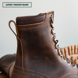 A close-up of a dark brown leather lace-up boot with a pull tab and decorative metal eyelets, shown against a light neutral background. A text label in the top left reads 'LEATHER: PREDATOR ORANGE'.