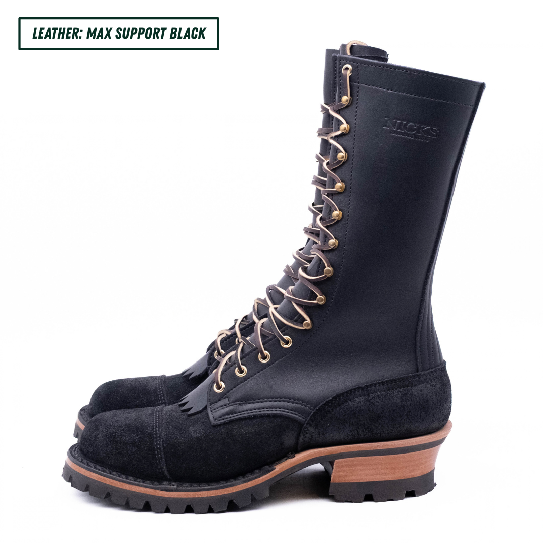 A pair of black leather and suede lace-up combat boots with gold-toned metal eyelets and a chunky lug sole, shown on a white background with a text label in the top-left corner.