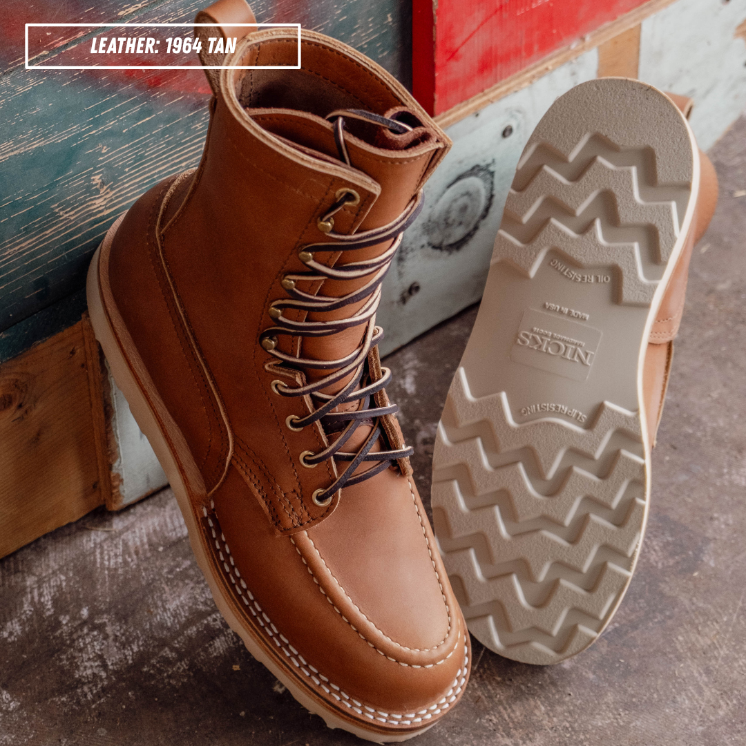 HD moc toe work boots, both sitting together with one upside down showing outsole on textured concrete. Label on top left of picture that reads "LEATHER: 1964 TAN."