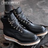 A pair of black leather lace-up ankle boots with white stitching and white soles, resting on a dark textured metal surface. A text overlay in the top-left corner reads 'LEATHER: MAX SUPPORT BLACK'.