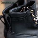Close-up of a black leather lace-up boot with metal eyelets and white laces, showing the ankle collar and pull tab, with a text label reading 'LEATHER: MAX SUPPORT BLACK' in the top-left corner.