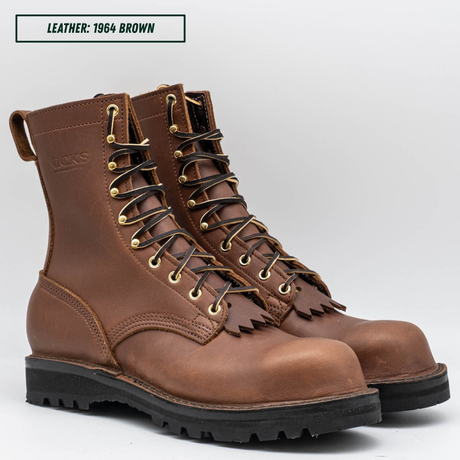 A pair of brown leather lace-up work boots with gold-toned metal eyelets and black soles, shown on a light gray background with a text label reading 'LEATHER: 1964 BROWN'.