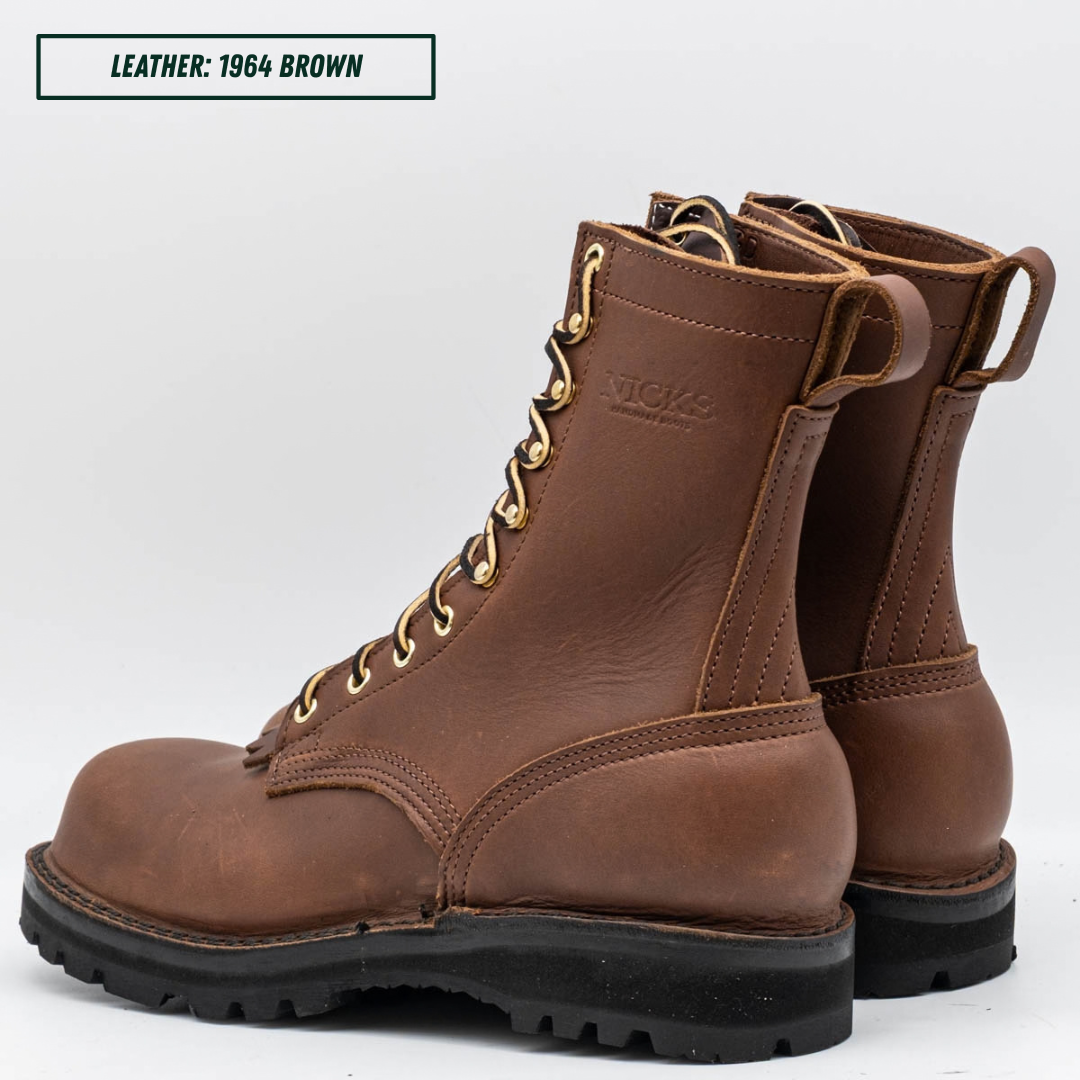 A pair of brown leather lace-up work boots with gold eyelets and black rubber soles, shown on a light gray background with a text label in the top-left corner that reads 'LEATHER: 1964 BROWN'.