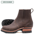 A dark brown leather Chelsea-style ankle boot with a chunky stacked heel, black lug sole, and a light tan midsole section. A black outsole is shown behind the main boot.