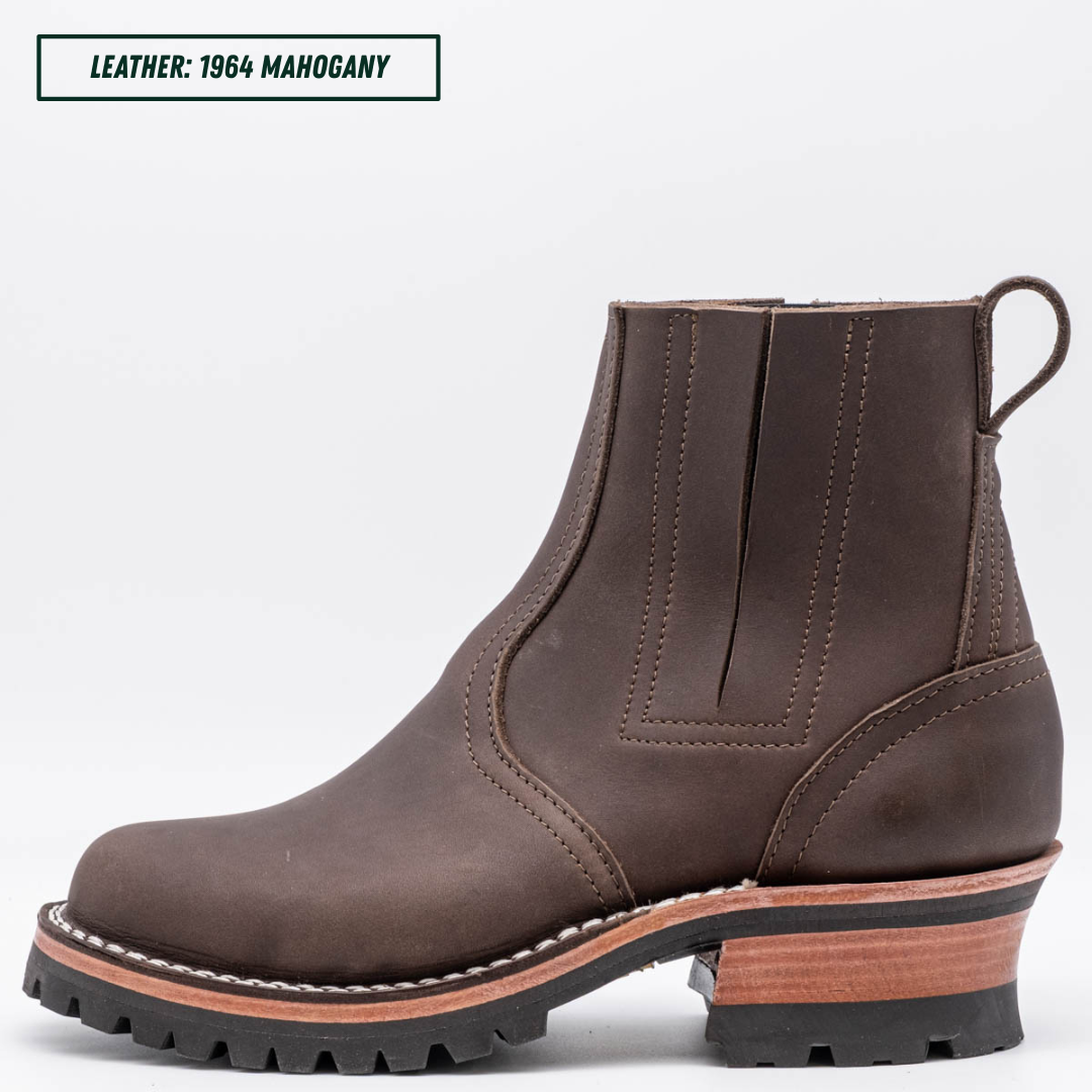 A dark brown leather Chelsea-style ankle boot with a chunky stacked heel, black lug sole, and a light tan midsole section. Top left reads "LEATHER: 1964 MAHOGANY."