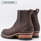 A dark brown leather Chelsea-style ankle boot with a chunky stacked heel, black lug sole, and a light tan midsole section. Boots sitting together facing back left. Top left reads "LEATHER: 1964 MAHOGANY."