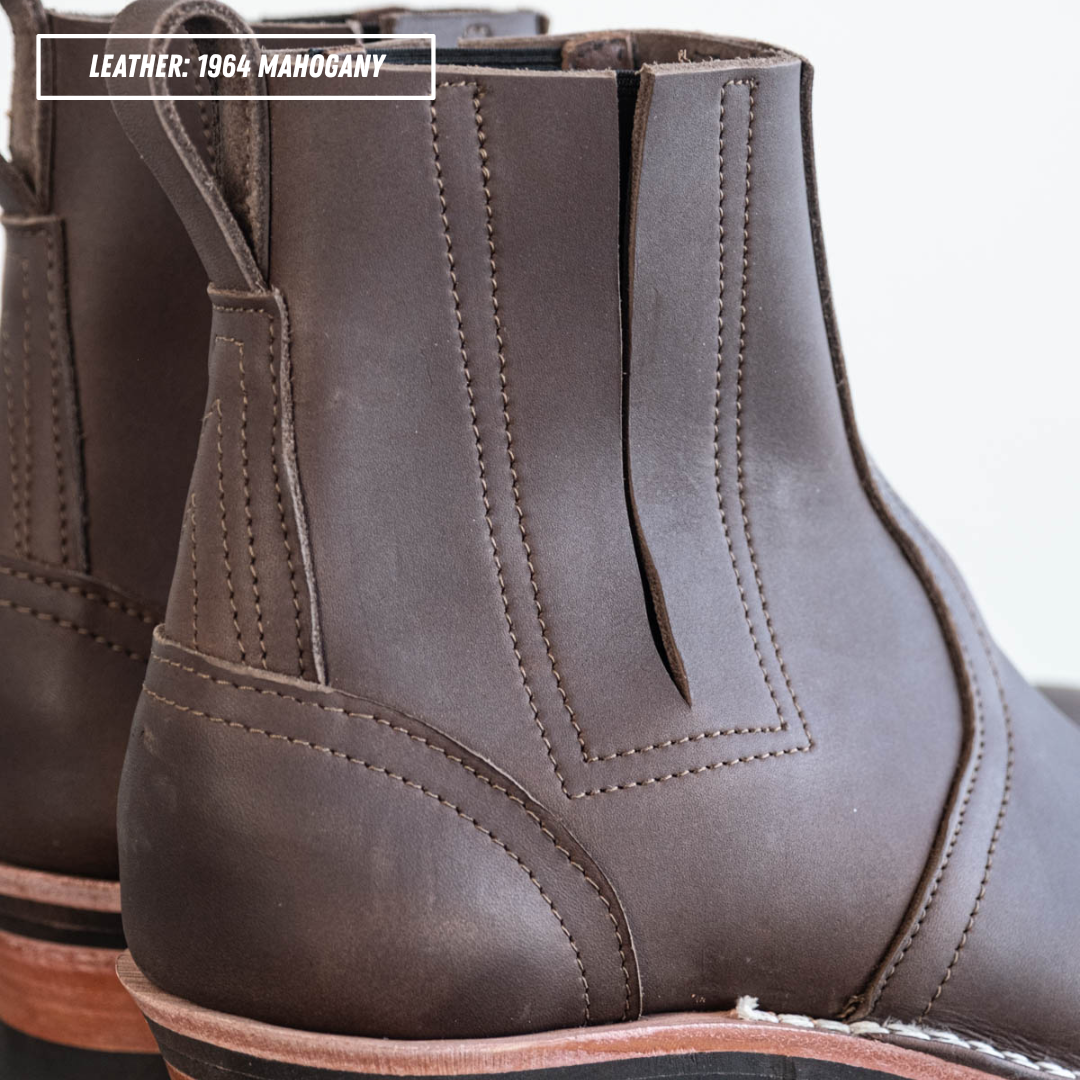 A close-up of a dark brown leather ankle boot, showing the side and heel details with a pull tab. A text overlay in the top left reads 'LEATHER: 1984 MAHOGANY'.