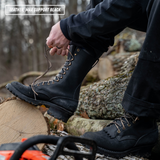 A person outdoors by a log wearing a black lace-up work boot and tying the laces. The boot is shown in use on a forest floor with tree trunks and branches in the background.