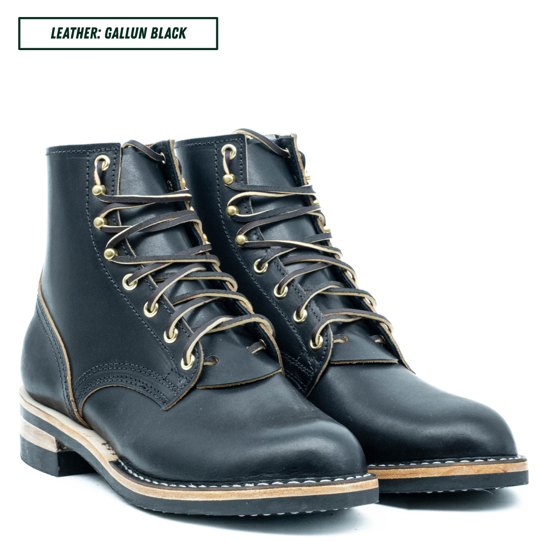 A pair of dark navy leather lace-up boots with gold-toned metal eyelets and a light tan welt, shown on a white background with a text label reading 'LEATHER: GALLUN BLACK'.