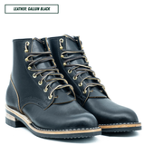 A pair of dark navy leather lace-up boots with gold-toned metal eyelets and a light tan welt, shown on a white background with a text label reading 'LEATHER: GALLUN BLACK'.