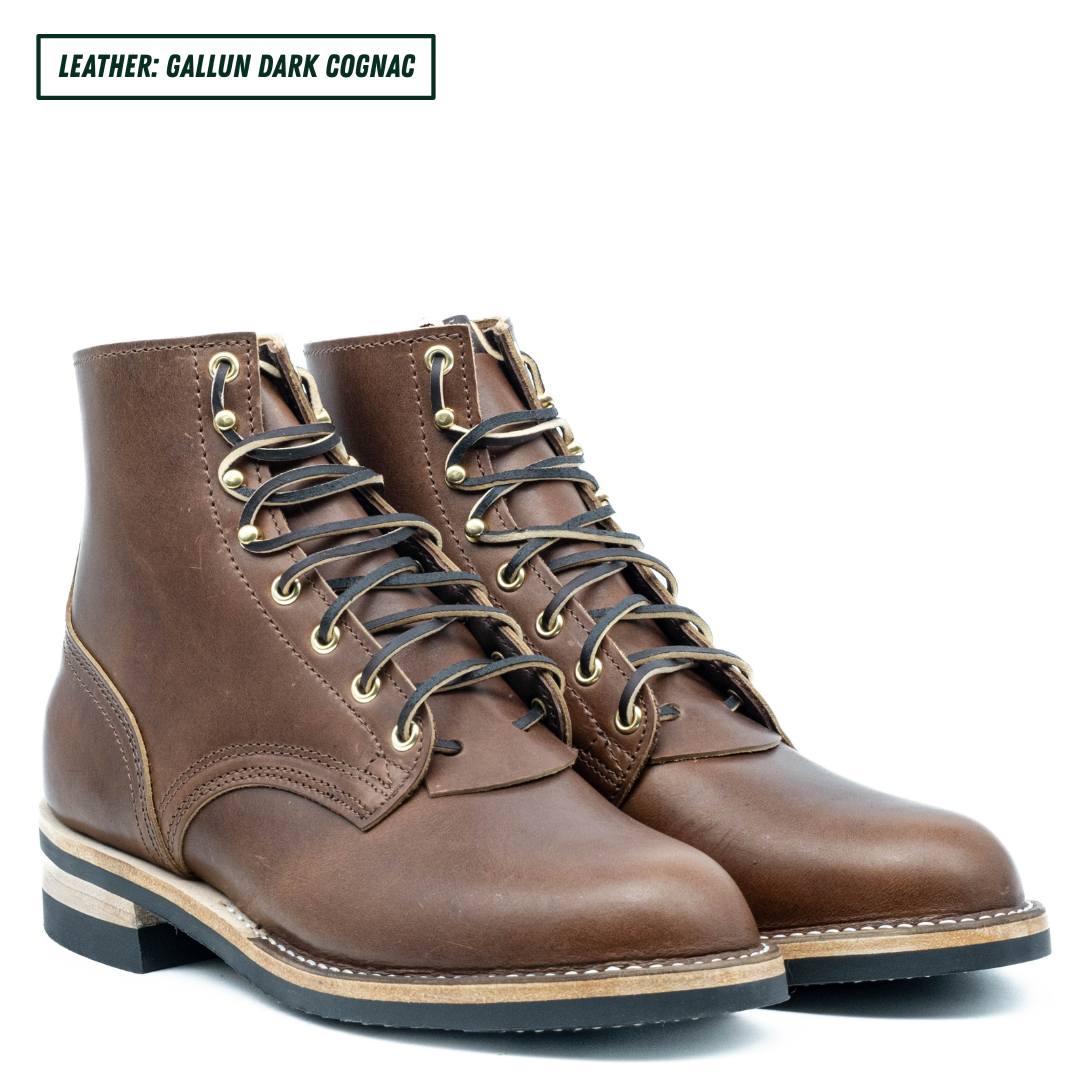 A pair of dark cognac brown leather lace-up ankle boots with brass eyelets and black laces, shown on a white background with a text label in the top left corner.