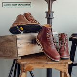 Two pairs of brown leather lace-up work boots displayed on rustic wooden crates and stools, with one boot showing its black treaded sole. Text in the top-left corner reads 'LEATHER: GALLUN CALF ASSORTED'.