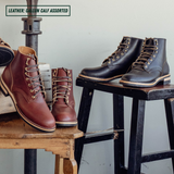 Two pairs of ankle boots in assorted brown and black shades displayed on rustic wooden stools and a metal stand against a light gray wall. A text label in the top left reads 'LEATHER: GALLUN CALF ASSORTED'.
