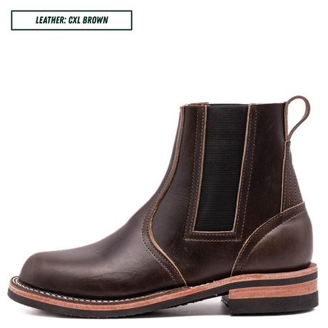 A dark brown leather Chelsea boot with a pull loop, elastic side gore, and stacked sole, shown in profile on a white background with a text label in the top-left corner.