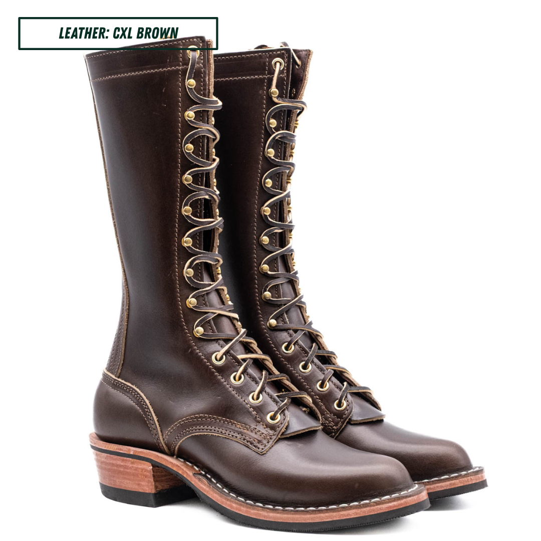 A pair of dark brown leather lace-up combat boots with gold-toned metal eyelets and a low stacked heel, shown on a white background with a text label in the top left corner.