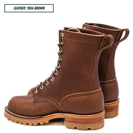 A pair of brown leather lace-up boots shown on a white background, with a text label in the top-left corner reading 'LEATHER: 1964 BROWN'. The boots feature tan laces, metal eyelets, a pull tab at the heel, and a thick lug sole.