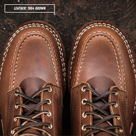 A close-up top-down view of a pair of brown leather lace-up shoes with white contrast stitching and dark laces, set against a dark textured background. A text label in the top left reads 'LEATHER: 1964 BROWN'.