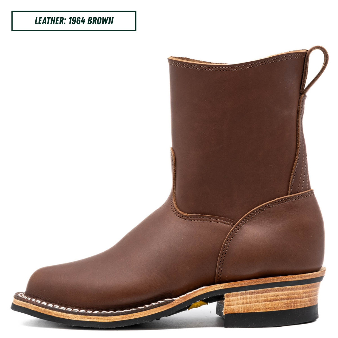 A brown leather ankle boot shown in profile against a white background, with a small text label in the top-left corner reading 'LEATHER: 1964 BROWN'. The boot has a rounded square toe, stitched seams, a pull loop at the back, and a stacked wood-look heel with a black outsole.