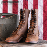 A pair of tall lace-up leather boots in a weathered brown finish, displayed on a wooden surface next to a vintage metal container with an American flag backdrop. A text overlay in the top-left corner reads 'LEATHER: WEATHERSHIELD BROWN'.