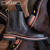 A pair of dark brown leather Chelsea boots with black elastic side panels and a layered sole featuring a light wood stripe, arranged in a pile with a text overlay that reads 'LEATHER: CXL BROWN'.