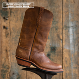 A single brown leather cowboy boot with a distressed finish, shown standing on a display stand against a rustic wooden plank background. A text overlay in the top-left corner reads 'LEATHER: PREDATOR ORANGE / SHRUNKEN BISON BROWN'.