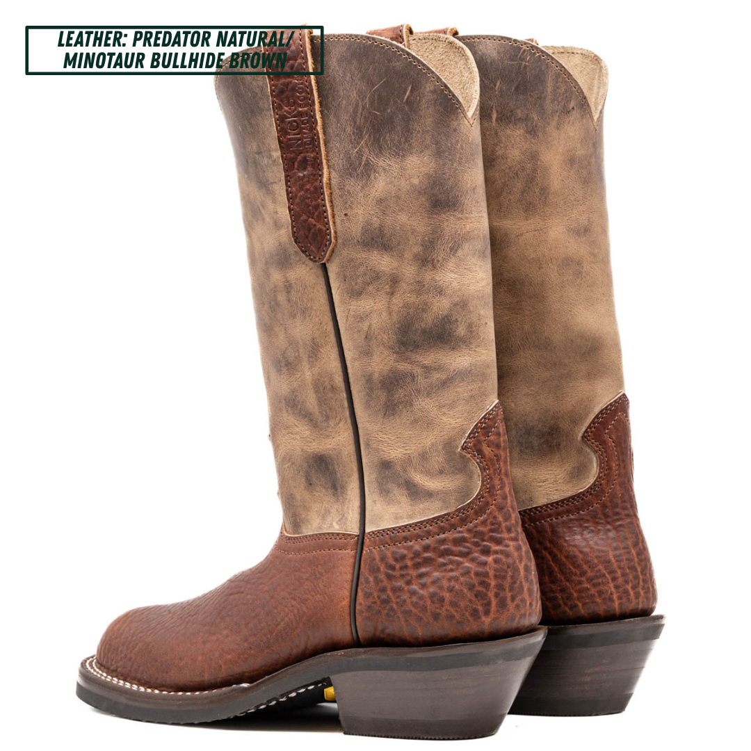 A pair of tall western cowboy boots shown from the side on a white background, with a text label in the top left reading 'LEATHER: PREDATOR NATURAL MINOTAUR BULLHIDE BROWN'. The boots have a distressed tan and brown leather shaft with a darker brown textured leather lower section and heel.