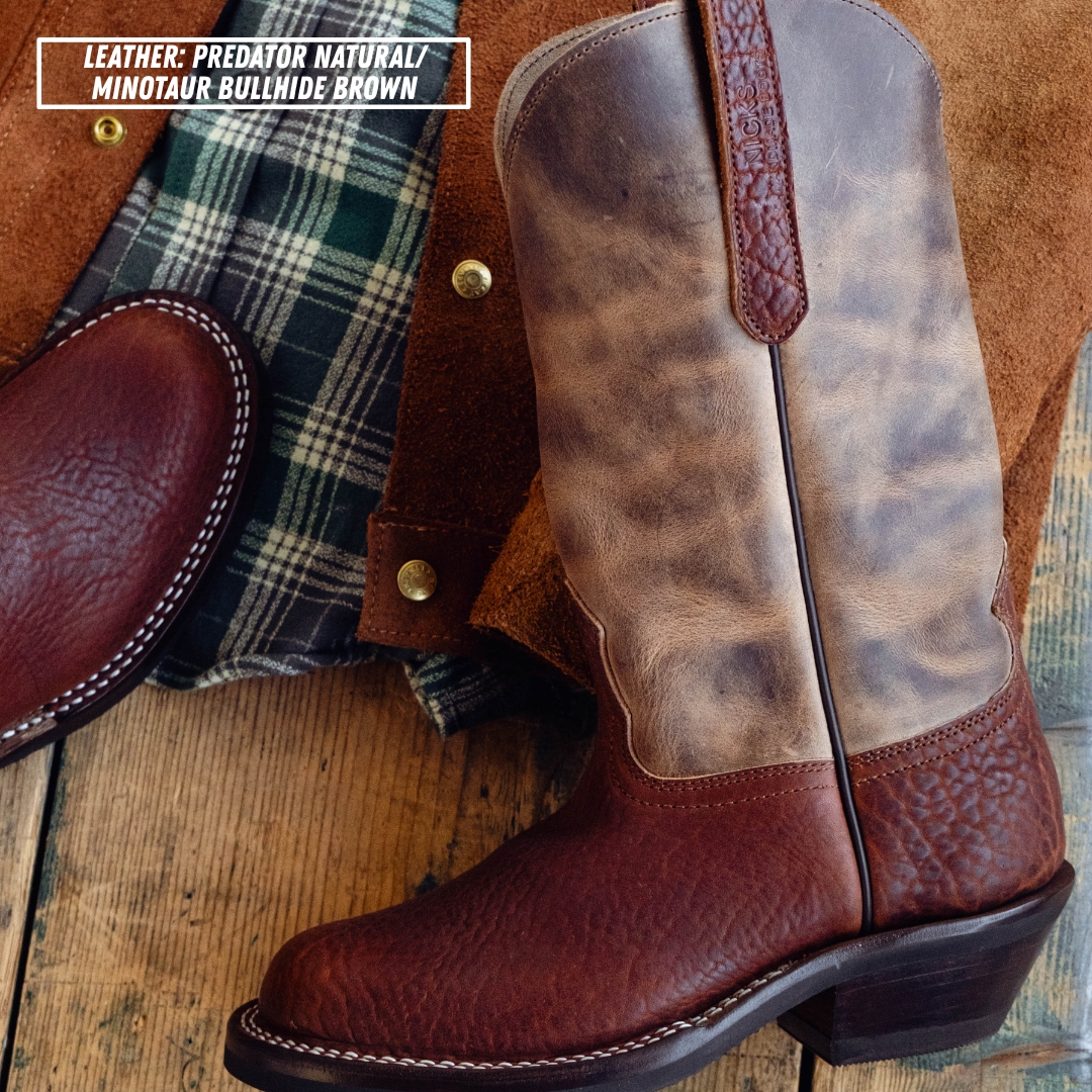 A leather cowboy boot in brown and tan distressed leather, shown alongside a matching brown leather pull tab and a green plaid shirt on a rustic wooden surface. A text overlay in the top left reads 'LEATHER: PREDATOR NATURAL / MINOTAUR BULLHIDE BROWN'.